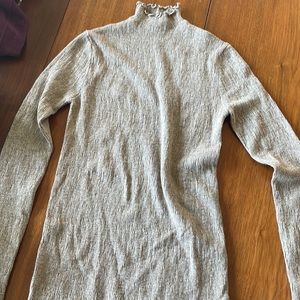 Tan turtleneck with ruffle detail around collar, hem and sleeves.